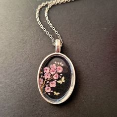 With an image of my flower illustration, I put my art into jewelry. This silver coloured necklace holds an oval pendant with a picture of my Cherry Blossom drawing. On top of the picture I have put a layer of Diamond glaze, (similar to resin) to prevent the image from fading and creating a hard and shiny surface. Breastmilk Pendant, Blossom Drawing, Cherry Blossom Drawing, Illustration Blume, Pendant With Chain, Crown Jewels, Colourful Necklace, Oval Pendant, Flower Illustration