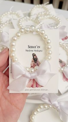 a hand holding a card with pearls and a bow on it that says, seray'in