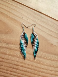 two pairs of blue and white beaded earrings sitting on top of a wooden table