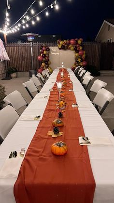 a long table is set up with pumpkins and candles for an outdoor dinner party