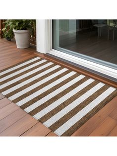 a brown and white striped rug sitting on top of a wooden floor next to a glass door