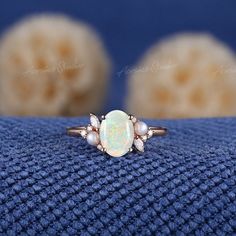 an opal and diamond ring sits on a blue cloth