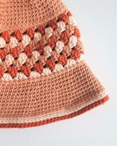 an orange and white crocheted hat hanging on a wall