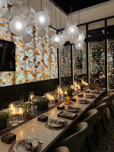 a long table with plates and candles on it in front of a large television screen