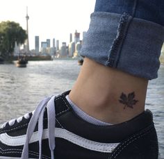 a woman's foot with a small leaf tattoo on her left ankle and the city skyline in the background