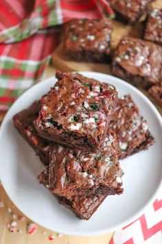 some brownies on a white plate with candy canes and peppermint sprinkles