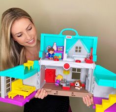 a woman holding up a doll house with her hands