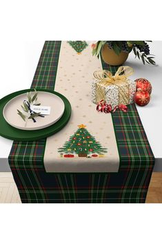 a table with a christmas tree on it and place setting next to the table cloth