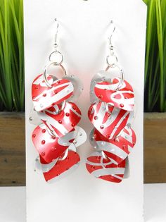 pair of red and silver heart shaped earrings on white card with grass in the background