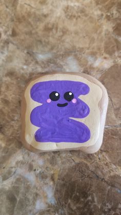 there is a purple bear on top of a toasted piece of bread that looks like it's smiling