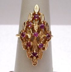 "This is a large, ornate ring from the 1970's. The ring is a large marquise shape and is made of small marquise shaped gold pieces put together in a clustered pattern. There are 9 round cut Rubies set in the open sections of the cluster design. The bottom of the ring has a cage with a cut out filigreed design. It gives the ring some visual side interest. Top of ring measures 1\" long. Ring is 14 karat yellow gold and weighs 6.5 grams. Ring is a size 7 1/2. *Sizing is available. Please message us Ornate Ring, Italy Jewelry, Gold Jewellry, Cluster Design, Long Ring, Diamond Wedding Sets, Gold Ring Designs, Jewellery Sets, Rings Cool