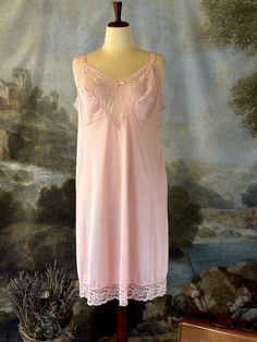 This 60s/70s Vassarette brand nightgown or slip is oh so pretty! The pink color is delicate and pairs perfectly with the sheer lace bust and matching hem. The v-neckline is set off by ribbon adjustable straps. Midi-length. Fits in an a-line style. This beautiful nightgown is perfect for anyone that loves vintage nightwear.   Brand: Vassarette       Fabric - 100% Nylon  No noticeable flaws - in great vintage condition  Size: Tag says size 42 - fits approximately like an XL (see measurements)   Measurements taken with garment lying flat: Underarm to underarm- 21"  Waist- 23.25" - can stretch to 24.5"  Hips- 26.74" - can stretch to 29"  Length- 39.75" *All vintage items are FINAL SALE. Please email with any questions before purchasing. We are happy to help with any inquires! *Please note that Vintage Lace Trim Slip Dress For Night, Coquette Nightgown With Lace Trim, 1940s Nightwear, Vintage Nightwear, Beautiful Nightgown, Pink Nightgown, Lace Slip Dress, Women's Nightgowns, Silk Slip Dress