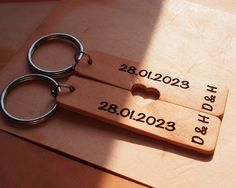 two personalized wooden keychains with the date and year engraved on them sitting on a table