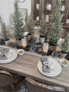 the table is set with pine cones and candles