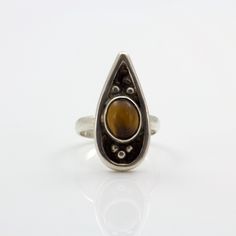 Discover the perfect blend of celestial charm and earthy elegance with our stunning Teardrop Tiger's Eye Ring. This unique piece features an 8x10mm oval Tiger's Eye cabochon, set in a sleek sterling silver band. The teardrop shape of the ring enhances the natural beauty of the Tiger's Eye, with its mesmerizing golden-brown hues and captivating chatoyancy. Ideal for those who love boho chic and earthy jewelry, this size 6.5 ring brings a touch of cosmic allure to any outfit. Whether you're dressing up for a special occasion or adding a statement piece to your everyday wear, this ring offers a sophisticated and versatile option. The sterling silver setting complements the rich tones of the Tiger's Eye, creating a piece that feels both luxurious and grounded. Embrace the beauty of the univers Adjustable Teardrop Jewelry With Polished Finish, Brown Teardrop Gemstone Jewelry, Vintage Teardrop Jewelry With Polished Finish, Silver Teardrop Cabochon Rings, Teardrop Cabochon Jewelry For Anniversary, Anniversary Teardrop Cabochon Jewelry, Brown Oval Gemstone Jewelry, Sterling Silver Teardrop Rings, Sterling Silver Teardrop Rings With Natural Stones