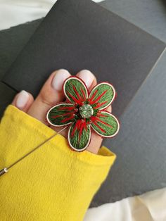 a hand holding a pin with a flower on it