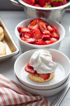 strawberry shortcakes with whipped cream and fresh strawberries in the background on a table