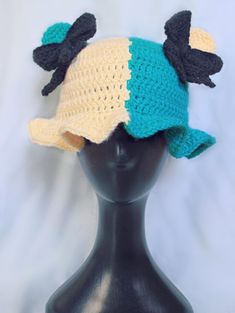 a crocheted hat with black bows on top of a mannequin head