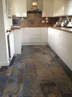 a kitchen with white cabinets and black slate tile flooring in it's center