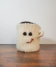 a crocheted coffee cup with a face drawn on it