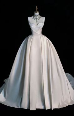 a white wedding dress on display in front of a black background with the back of it's neckline