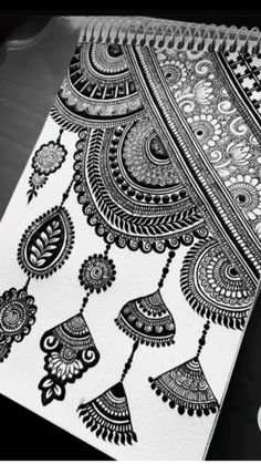 a black and white drawing on top of a notebook with an intricate design in the middle