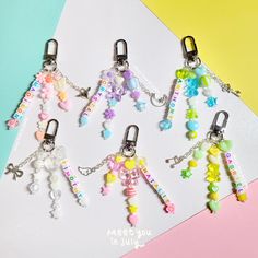 four key chains with charms attached to them on a table next to a colorful background