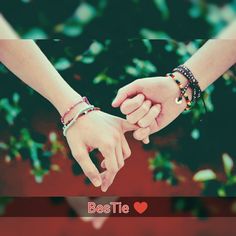 two people holding hands with the words bestie written on them and green leaves in the background