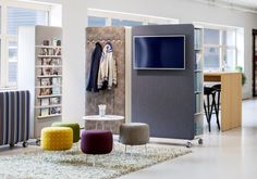 a room with several different colored chairs and tables in front of a wall mounted television