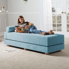 a woman sitting on a couch reading a book