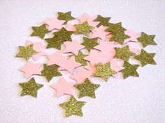 pink and gold stars are scattered on a white table top with glitter flecks