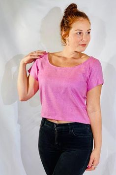 a woman in black jeans and a pink shirt is posing for the camera with her hand on her hip