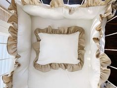 a square pillow with ruffles on it in front of a white wall and window