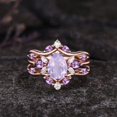 a ring with an amethorate surrounded by pink and white stones on a rock