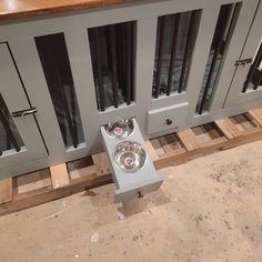 the dog bowls are placed on the floor in front of the large gray cabinet with sliding glass doors