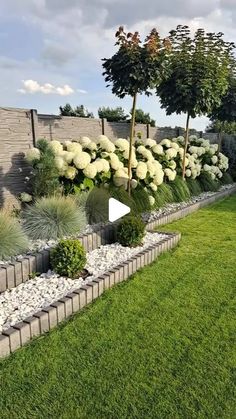 a garden with lots of plants and rocks in it's center, next to a fence