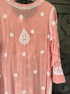 This Pastel Pink crepe silk dress is a charming addition to any wardrobe. The intricate embroidery and beautiful pastel pink color make it a truly unique and eye-catching piece. Wear yours with white straight pants and white chiffon dupatta for a traditional look. 46" length Long sleeves 20" Round neck Crepe silk Side slits Dry clean Chikankari embroidery Hand embroidered Fit: True to sizeInside Margin: NoTouch and Feel: Soft and ComfortableDispatched in 1-3 business days Long Kurta With Intricate Embroidery For Spring, Pink Bohemian Embroidered Dress For Festivities, Pink Bohemian Embroidered Dress For Festive Occasion, Festive Bohemian Pink Embroidered Dress, Traditional Pink Dress With Intricate Embroidery, Traditional Pink Embroidered Dress With Dabka Work, Pink Embroidered Dress With Intricate Details, Traditional Pink Embroidered Fitted Dress, Traditional Fitted Pink Embroidered Dress