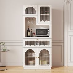 a white cabinet with wine glasses and a microwave on top is in the middle of an empty room