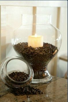 a glass bowl filled with coffee beans and a lit candle