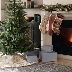 a christmas tree with stockings hanging from it's sides in front of a fireplace