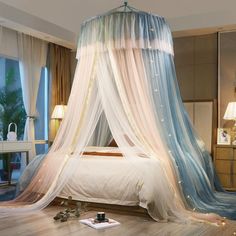 a bedroom with a bed covered in sheer curtains and pillows on the floor next to two lamps