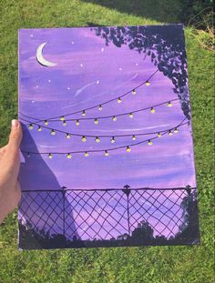 someone is holding up a purple canvas with string lights and the moon in the sky