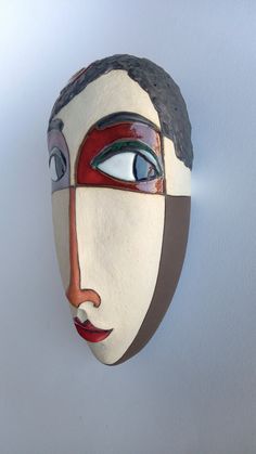 a mask is hanging on the wall and has eyes painted red, white, and blue