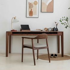 a desk with a laptop on it and two pictures hanging above the desk in front of it