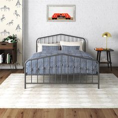 a bedroom with a metal bed frame and blue bedspread in front of a white brick wall