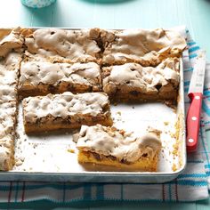 a pan filled with brownies and frosting on top of a blue table cloth