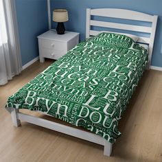 a bed in a room with blue walls and wooden flooring that has green letters all over it