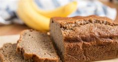 a loaf of bread sitting on top of a wooden cutting board next to two bananas