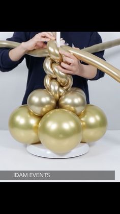 a woman is holding some balloons in front of her face and standing on a white plate