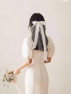 a woman in a white dress is holding a bouquet and looking down at the ground